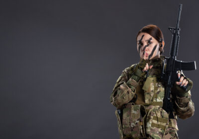 front view female soldier with machine gun camouflage dark wall